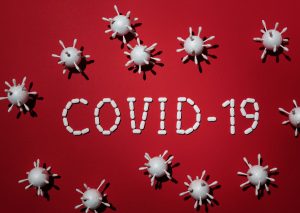czerwona plansza z napisem covid-19 i bakteriami